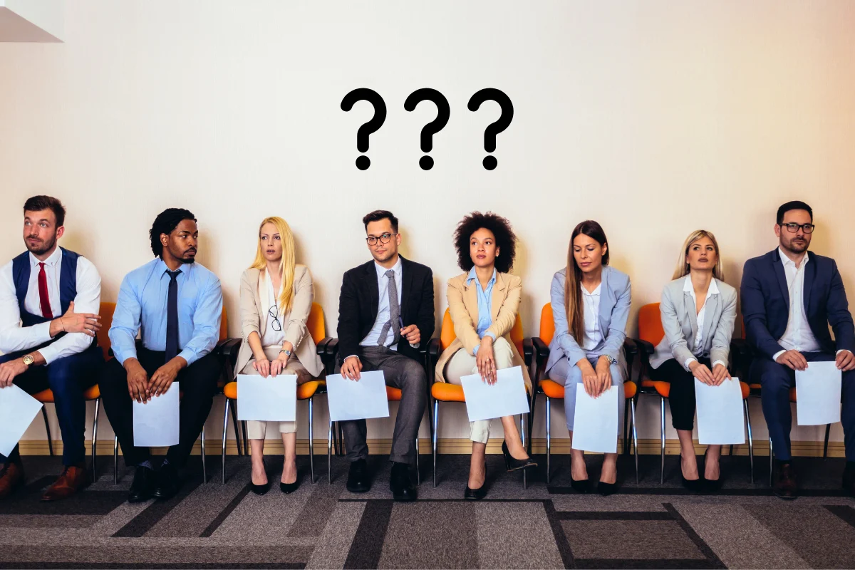 People sitting in a row waiting to be interviewed with questions marks above reflecting the question - Why is so hard to hire in 2026?